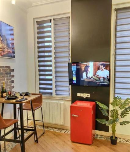a living room with a red refrigerator and a tv at Studio le petit nid douillet - Centre ville in Les Andelys