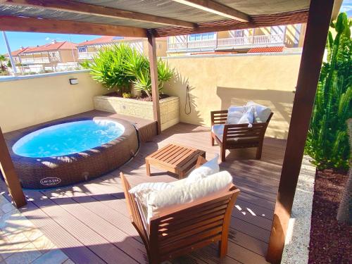 a patio with a hot tub and chairs on a deck at Medano Beach - Villa Playa in El Médano
