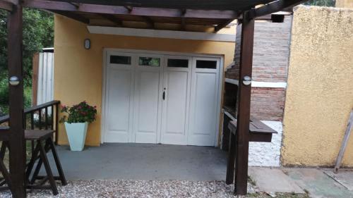 a garage with a white door and a wooden pergola at Las Hortensias Monoambiente in La Pedrera