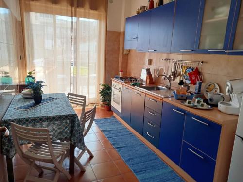 a kitchen with blue cabinets and a table with chairs at La Casa del Sole in Giarre