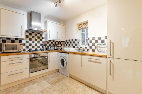 a kitchen with white cabinets and a washer and dryer at Broads Reach - Norfolk Holiday Properties in Stalham