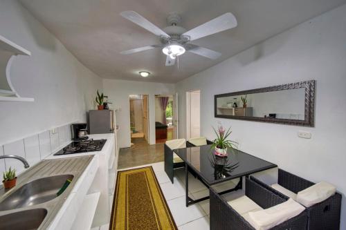 a living room with a ceiling fan and a kitchen at Jungle's Edge in Nosara