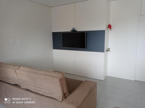 a living room with a couch and a tv on a wall at Apartamento FLAT no centro - Passo de Torres SC in Pirataba