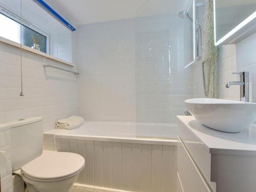 a white bathroom with a toilet and a sink at Erin Cottage in Pelynt