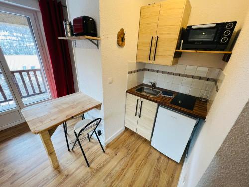 a small kitchen with a table and a sink at Studio Montagne - Plein Soleil et Terrasse in Briançon