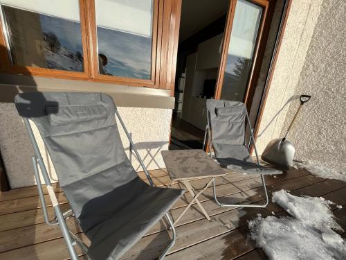 two chairs sitting on a porch next to a window at Appartement avec Terrasse - Soleil des Alpes - Orcières-Merlette 1850 in Orcières