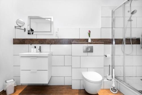 a white bathroom with a toilet and a shower at Pension Genat in Wedemark