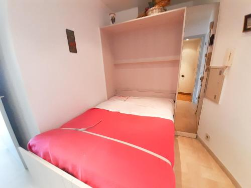 ein kleines Schlafzimmer mit einem roten Bett in einem Zimmer in der Unterkunft Trident A in Cannes
