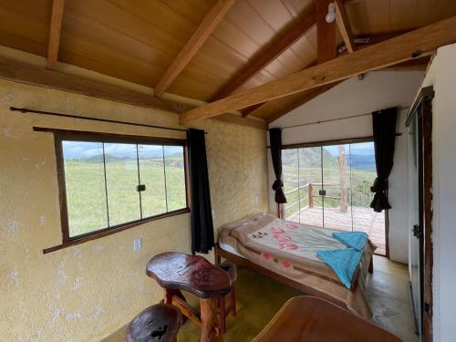 サン・ジョルジェにあるChalé Beija Flor, venha viver essa experiência!!のベッドと窓が備わる小さな客室です。