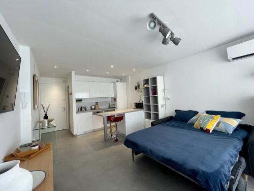 a bedroom with a blue bed and a kitchen at Sea view apartment, huge terrace on the 4th floor in Menton