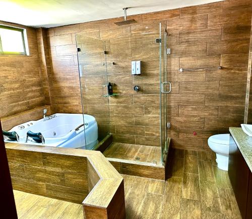 y baño con bañera, ducha y aseo. en Hermoso departamento con jacuzzi privado, en Quito