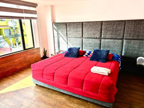 1 dormitorio con cama roja y almohadas azules en Hermoso departamento con jacuzzi privado, en Quito