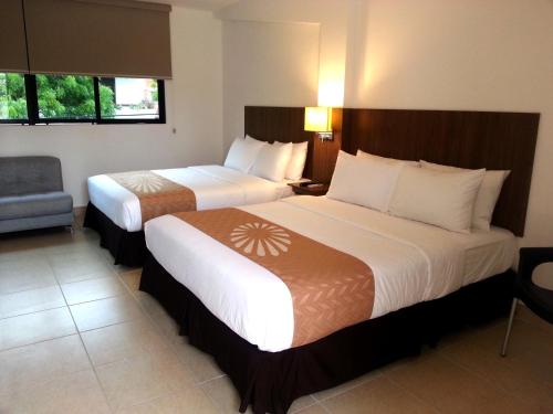 une chambre d'hôtel avec deux lits et une chaise dans l'établissement Buenavista Place Hotel, à Bahía de Caráquez