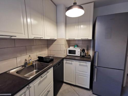 a kitchen with white cabinets and a sink and a refrigerator at Appartement Noisiel 77 (proche Disneyland & Paris) in Noisiel