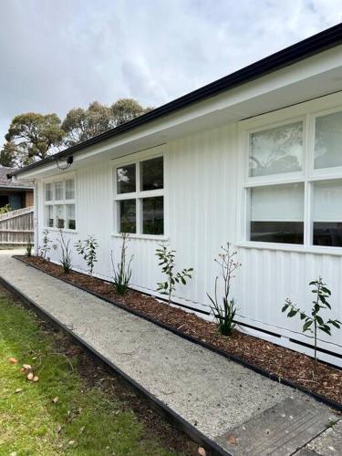 a white house with windows and a sidewalk at Pet friendly, Family home close to town in Cowes
