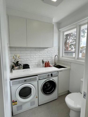 a white kitchen with a washing machine and a sink at Pet friendly, Family home close to town in Cowes