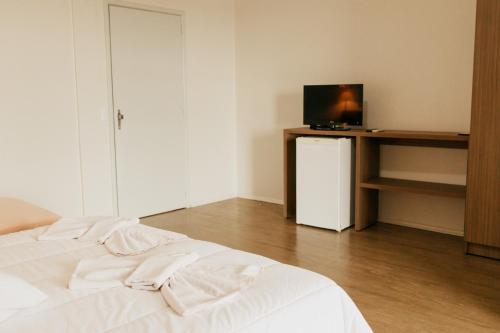 a bedroom with a white bed and a television at Rigo Hotel in Santa Rosa