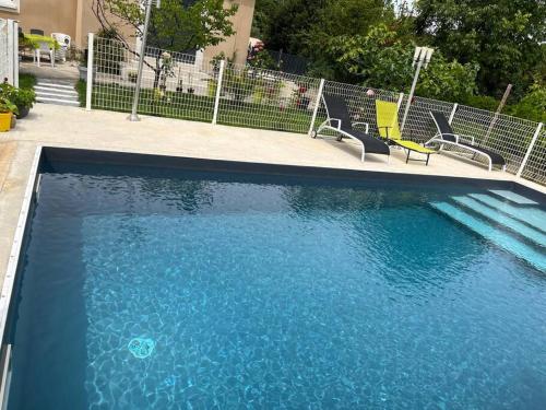 basen z niebieską wodą i krzesłami w obiekcie Villa climatisé avec piscine et jacuzzi w mieście Carpentras
