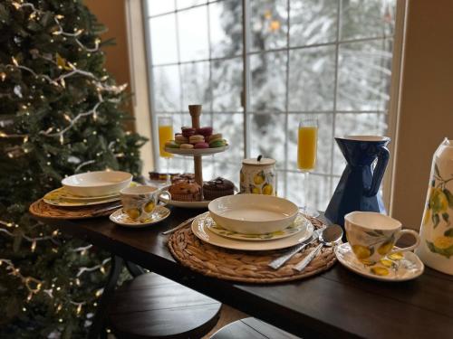 une table avec des assiettes et des tasses et un arbre de Noël dans l'établissement YoBee! Park Reservation Included! Heart of Yosemite - Homey Studios and Breakfast, à Yosemite West