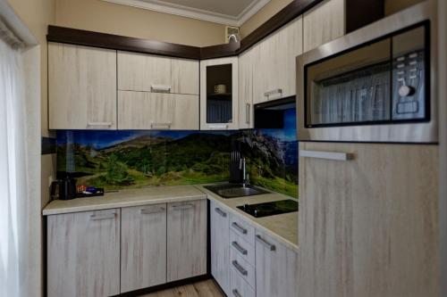 eine Küche mit Holzschränken und einer Mikrowelle in der Unterkunft Marmaros Apart-Hotel & Spa in Bukowel