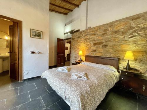 a bedroom with a large bed and a stone wall at La Alberguería complejo rural in Cañamero