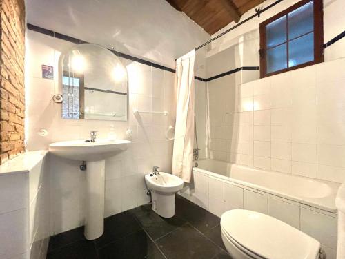 La salle de bains blanche est pourvue d'un lavabo et de toilettes. dans l'établissement La Alberguería complejo rural, à Cañamero