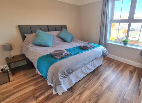 a bedroom with a bed with blue pillows and a window at Castle Cottage in Rayleigh