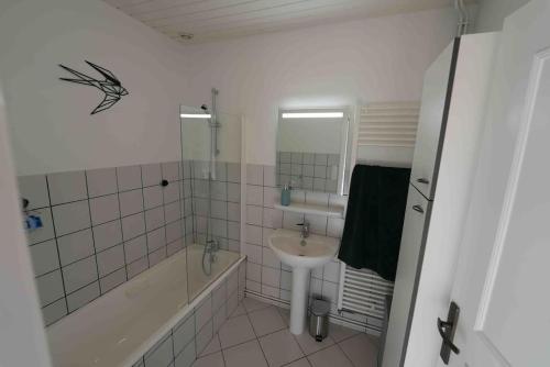 La salle de bains blanche est pourvue d'un lavabo et d'une baignoire. dans l'établissement Votre appartement à Chalmazel, à Chalmazel