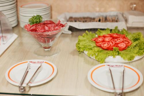 a table with plates and a bowl of lettuce and tomatoes at Rigo Hotel in Santa Rosa