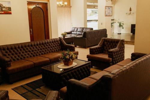 a living room with brown leather couches and chairs at Rigo Hotel in Santa Rosa