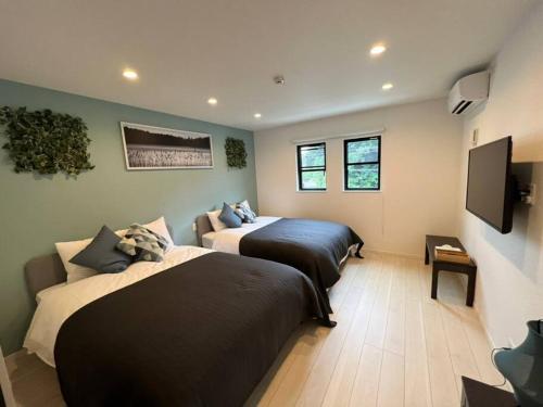 a bedroom with two beds and a flat screen tv at Ms. White Beach Resort in Kanayama