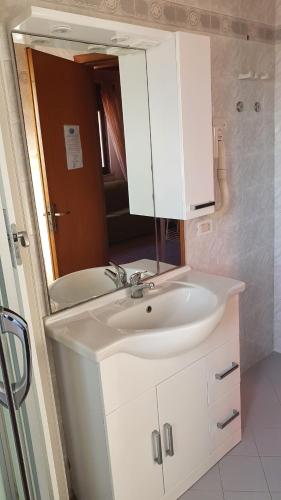 Un baño con un lavabo blanco y un espejo. en Residence Villa delle Rose, en Lampedusa