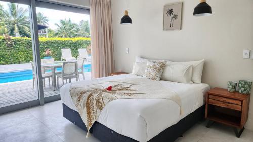 a bedroom with a bed and a balcony with a table at Mama Taras Luxury Villa in Ngatangiia