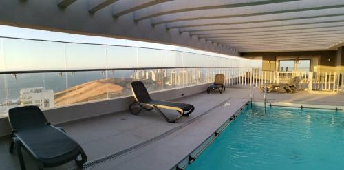 un edificio con piscina y sillas en el balcón en Exquisito Departamento Reñaca en el sector más turístico, en Viña del Mar