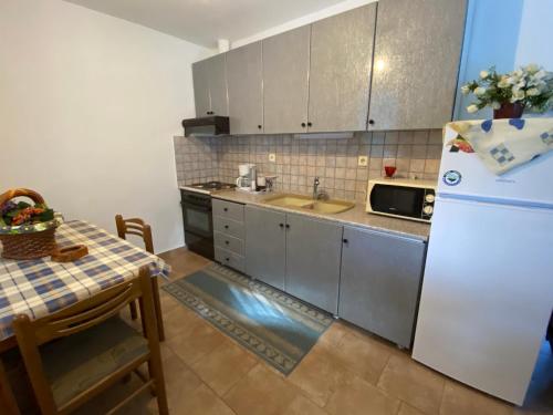 a kitchen with a table and a white refrigerator at HOUSE BTS(BY.THE.SEA) in Stavros