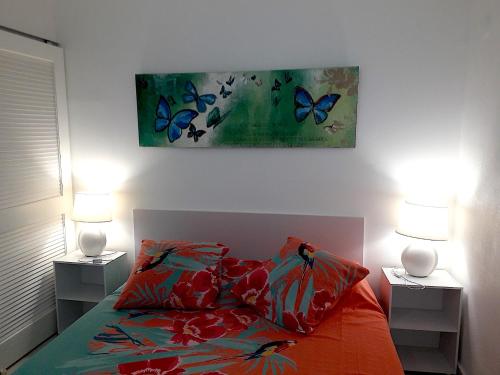 1 dormitorio con 1 cama con 2 lámparas y 1 pintura en le BLUE LAGOON, en Saint Martin