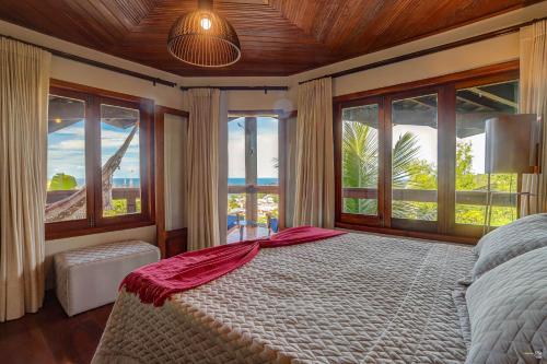 a bedroom with a large bed and large windows at Chocolate Hotel in Itacaré