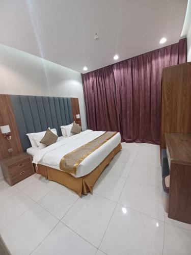 a bedroom with a large bed and purple curtains at شاليهات سرايا ان لبيوت العطلات in Jazan