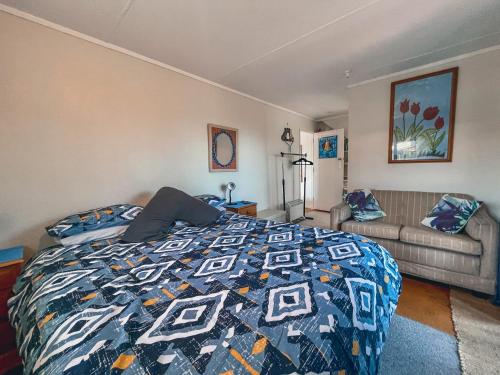 um quarto com uma cama e um sofá em Waihi Beach B&B em Waihi Beach