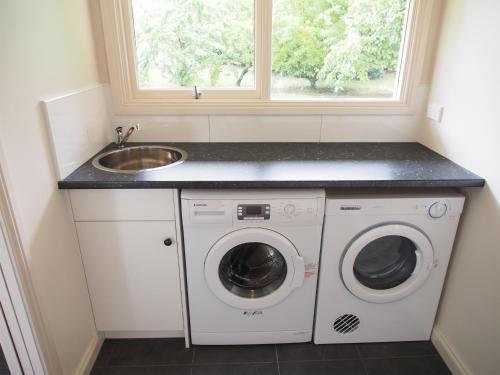 a kitchen with a sink and a washing machine at Tahara Cottage in Deloraine