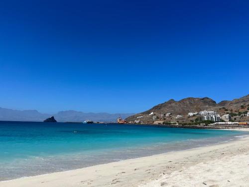 a beach with blue water and mountains in the background at Orietta Residencial in Mindelo
