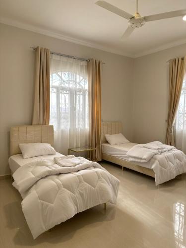 2 Betten in einem weißen Zimmer mit Fenster in der Unterkunft Homely.8 شقة in Firq