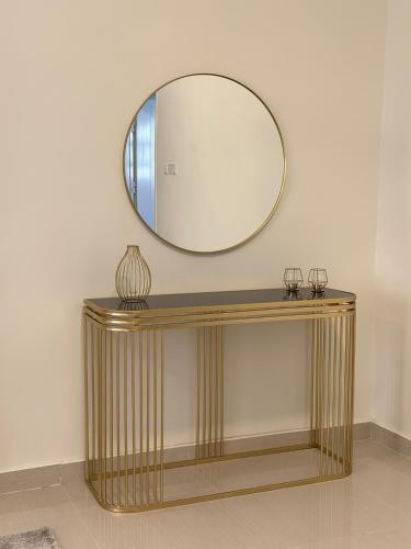 ein Spiegel an einer Wand über einem goldenen Konsole-Tisch in der Unterkunft Homely.8 شقة in Firq
