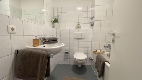 ein weißes Bad mit einem WC und einem Waschbecken in der Unterkunft Strandhaus Nordseebrandung Fewo A2.4 in Cuxhaven