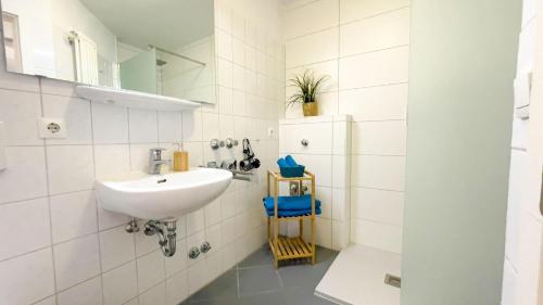 ein weißes Badezimmer mit einem Waschbecken und einem Spiegel in der Unterkunft Strandhaus Nordseebrandung Fewo B1.4 in Cuxhaven