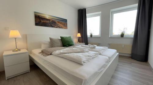 ein großes weißes Bett in einem Zimmer mit Fenstern in der Unterkunft Strandhaus Nordseebrandung Fewo B1.4 in Cuxhaven
