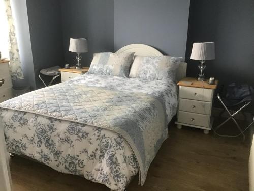 a bedroom with a bed and two night stands with lamps at TJ’s Cottage in Enniskillen