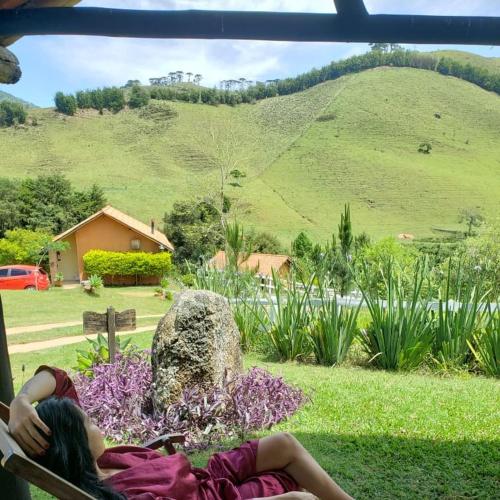 a woman laying on a bench looking at a hill at Pousada Vale Monte Azul in Santo Antônio do Pinhal