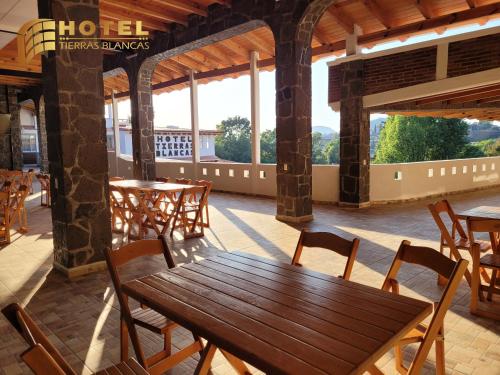 a wooden table and chairs in a room with windows at Hotel Tierras Blancas in Valle de Bravo