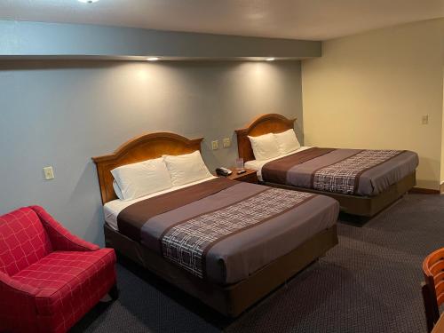 una habitación de hotel con 2 camas y una silla en Campus Inn Baraboo en Baraboo